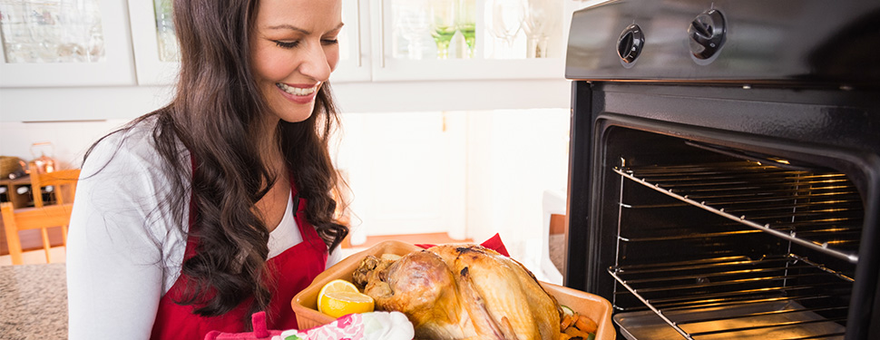 woman placing a turkey in the oven