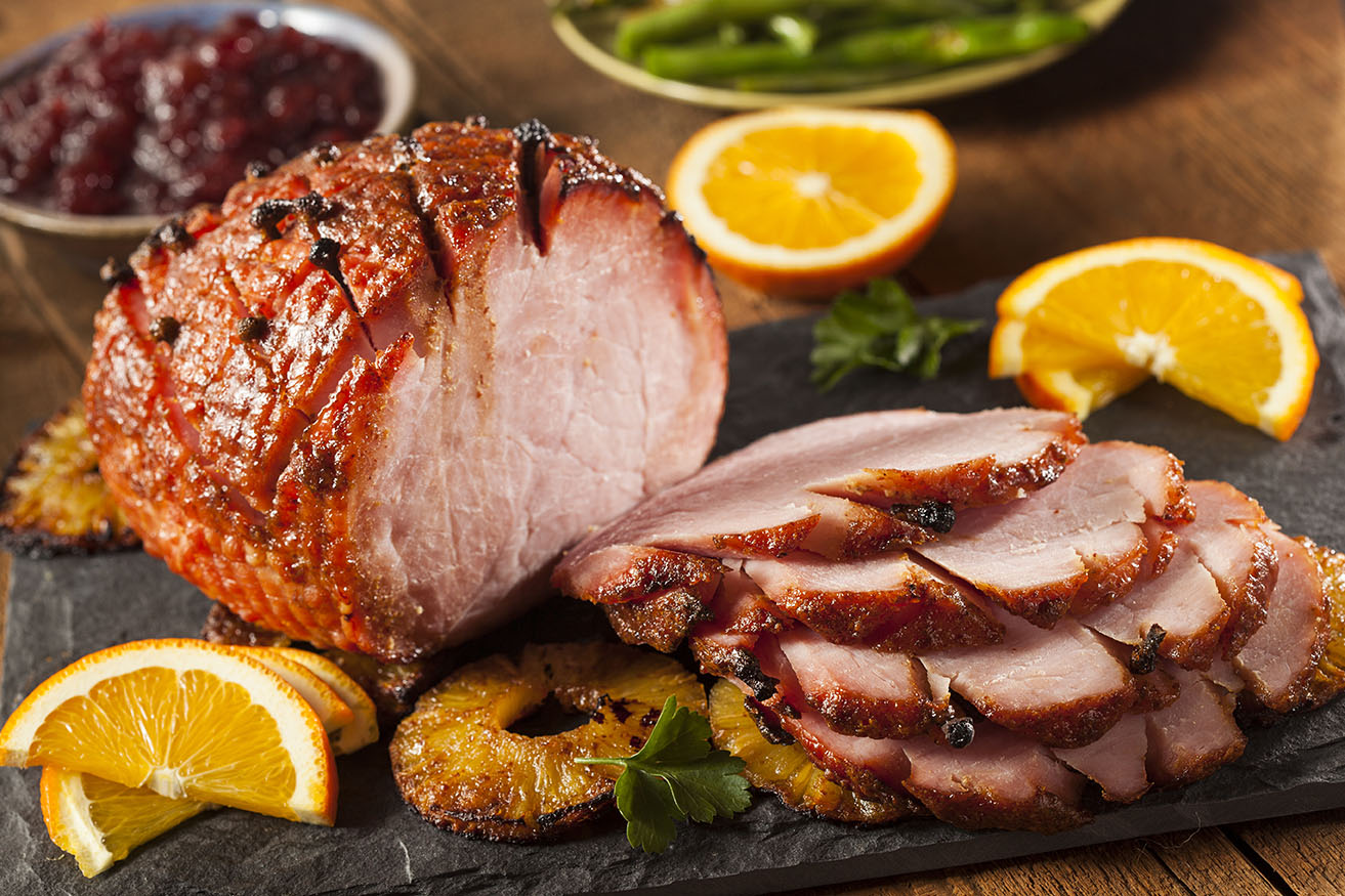 cut ham with oranges on a platter